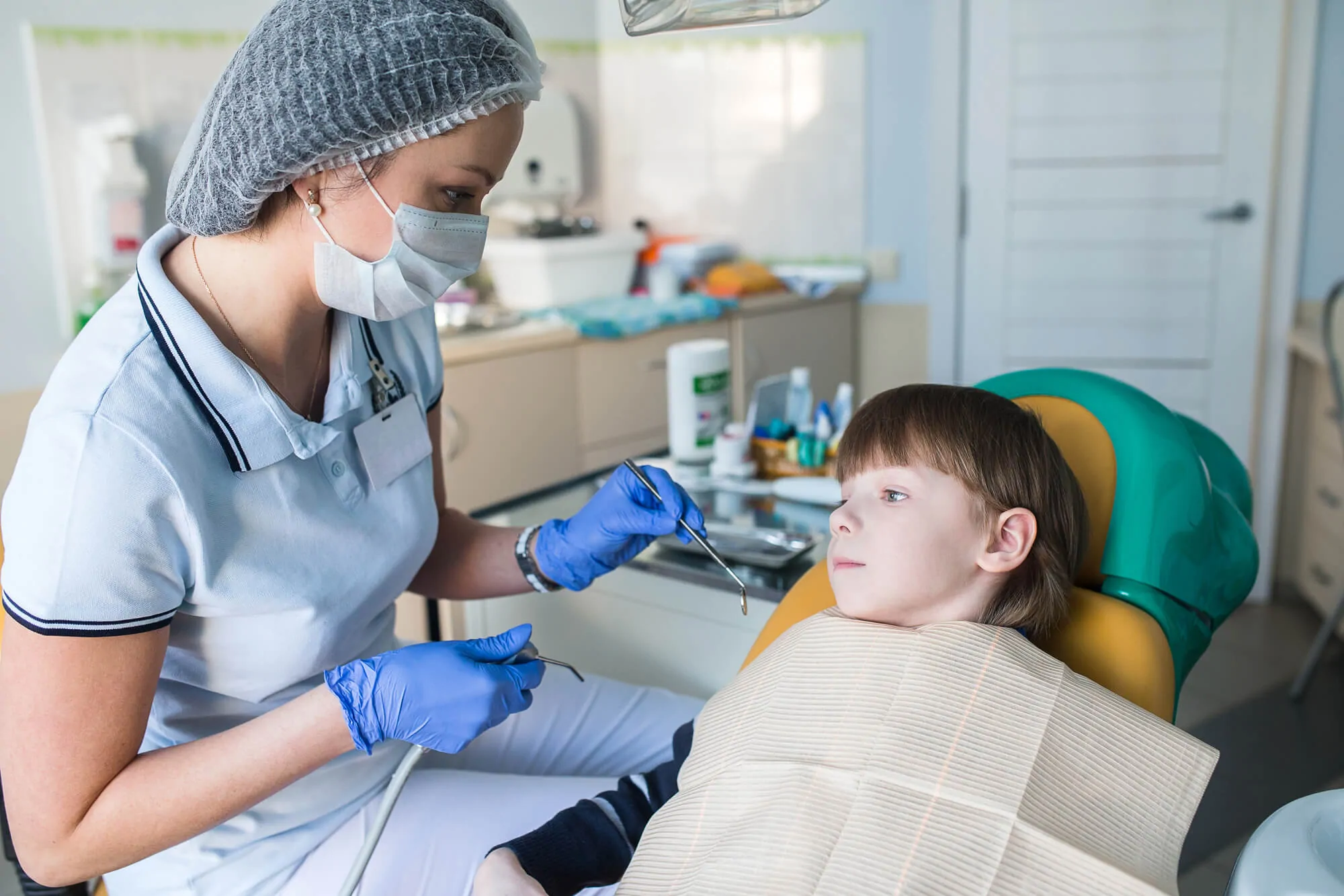 Lufkin Kids Dentistry team member gives a hands on demonstration what the teeth cleaning tool feels like to a pediatric patient in the treatment room
